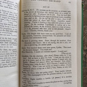 May include: A vintage book with a worn cover, titled "The Cherry Orchard" by Anton Chekhov. The book is open to page 43, showing Act IV of the play. The text is in black and white, with a few illustrations.
