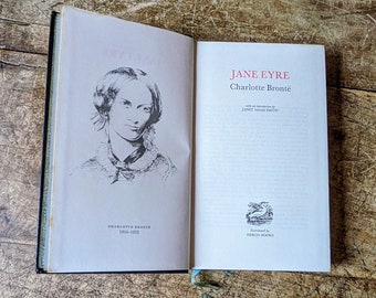 May include: A vintage paperback copy of Jane Eyre by Charlotte Bronte with an introduction by Janet Adam Smith. The cover features a black and white illustration of Charlotte Bronte and the text "Jane Eyre" and "Charlotte Bronte" in red.