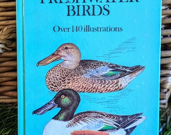 May include: A blue book titled "Marshland and Freshwater Birds" with a color guide to familiar birds. The book cover features illustrations of two ducks, one with a brown and green body and the other with a brown and orange body. The book states that it has over 140 illustrations.