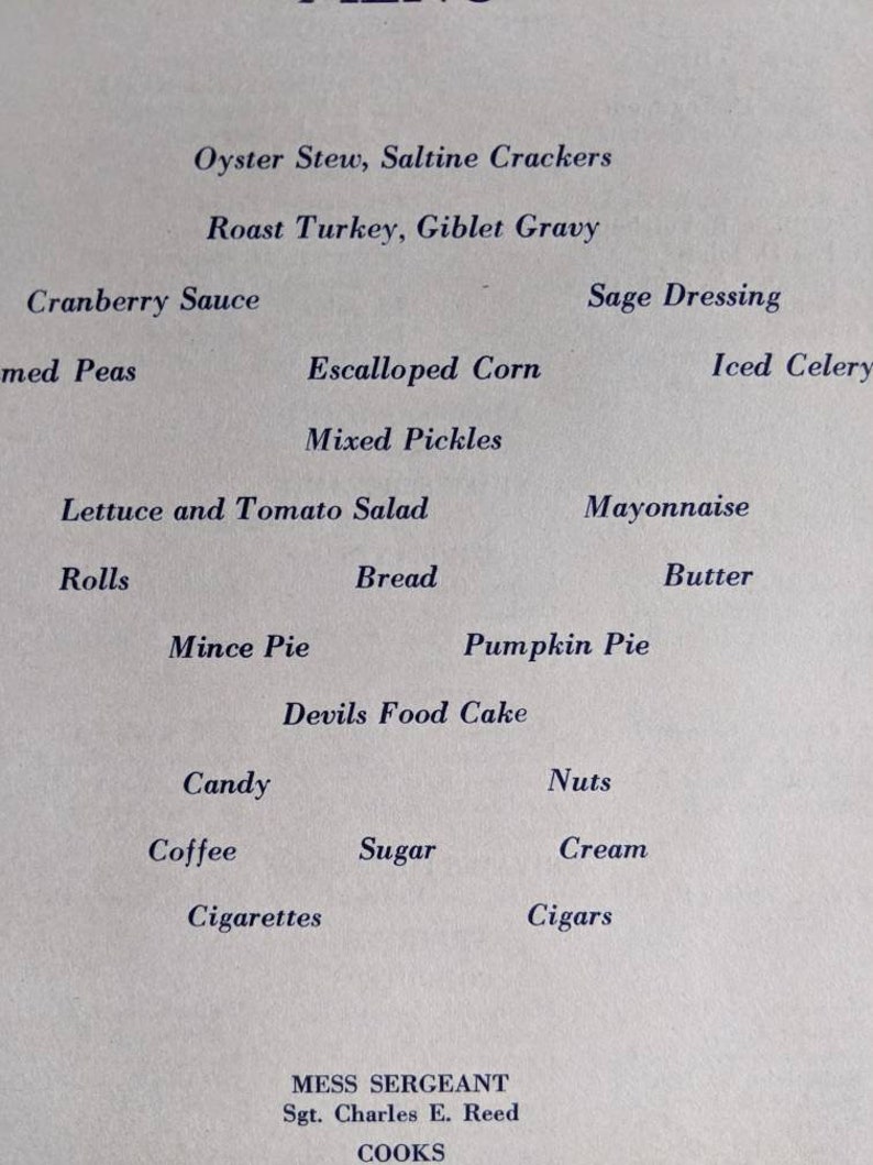 May include: A vintage menu printed on cream-colored paper. The menu lists various dishes, including Oyster Stew, Roast Turkey, and Pumpkin Pie. The text is in a classic serif font. The menu is signed by Mess Sergeant Sgt. Charles E. Reed.