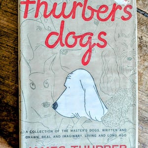 May include: Vintage book cover titled "Thurber's Dogs" with red lettering and illustrations of various dog breeds. The cover features a drawing of a white dog's head. The author's name, James Thurber, is printed at the bottom.