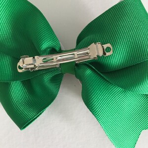 May include: A green hair bow with a silver alligator clip.