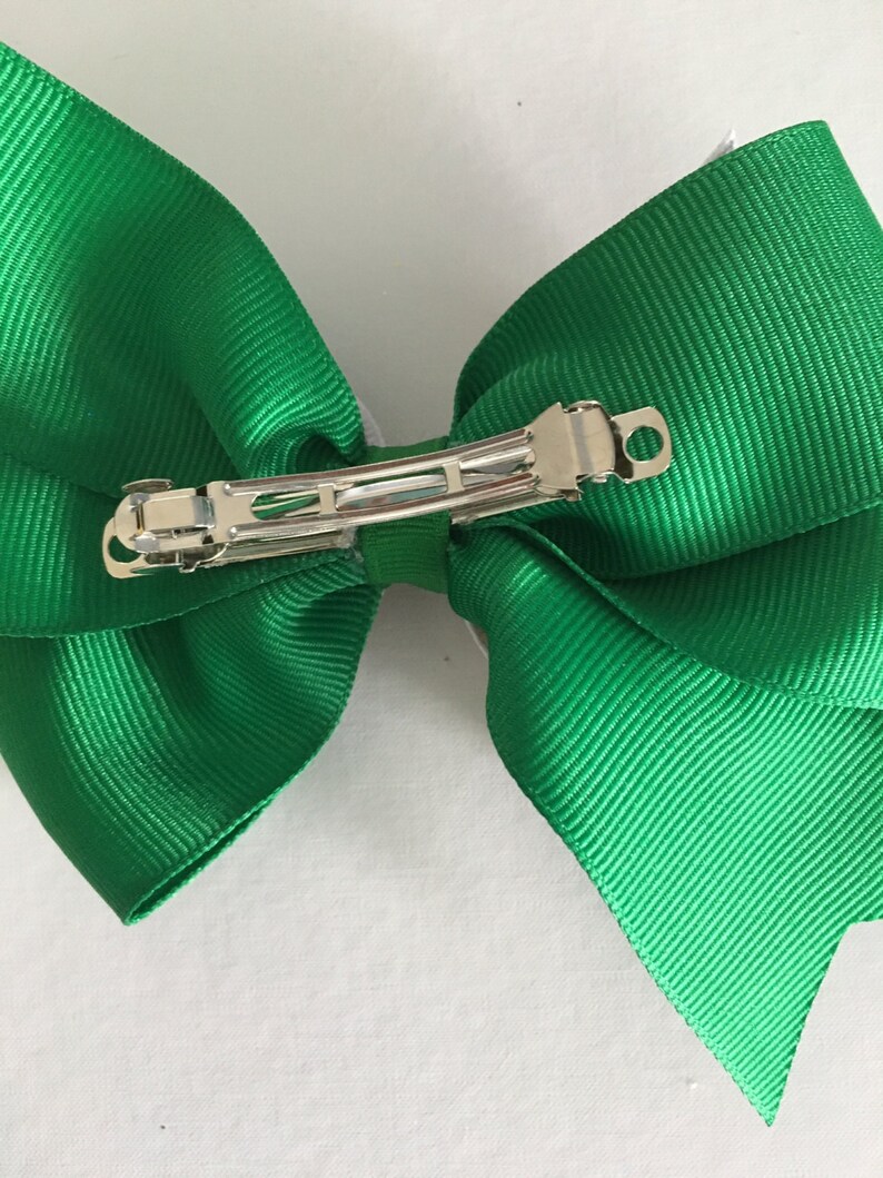 May include: A green hair bow with a silver alligator clip.