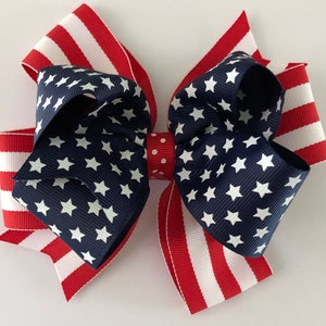May include: A red, white, and blue bow with a star pattern. The bow is made of ribbon and is tied in a knot. It is a patriotic decoration.