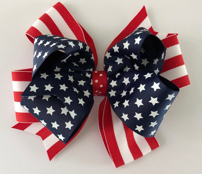 May include: A red, white, and blue bow with a star pattern. The bow is made of ribbon and is tied in a knot. It is a patriotic decoration.
