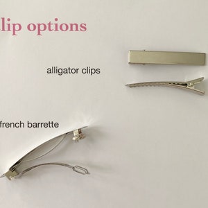 May include: Image showing hair clip options: alligator clips and a French barrette. The text "clip options" is in pink, with the words "alligator clips" and "french barrette" in black. The clips are silver and sit on a white background.