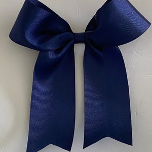 May include: A large navy blue satin bow with two long tails.