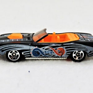 May include: Black and silver toy car with orange interior and a blue and red swirl design. The car is a convertible and has a black hood scoop.
