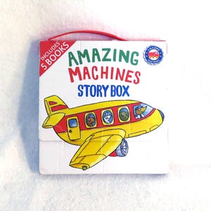 May include: A square white cardboard story box with a red plastic carrying handle. The front features the text Amazing Machines Story Box and a colorful illustration of a yellow airplane with animal passengers. A red corner label reads Includes 5 Books.