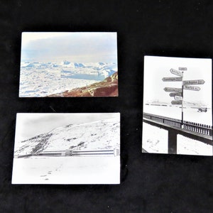 May include: Three vintage postcards showing snowy landscapes. The first postcard shows a snowy mountain range with a glacier in the distance. The second postcard shows a building in a snowy landscape. The third postcard shows a signpost with arrows pointing in different directions, with the text "Copenhagen 11 hrs", "Los Angeles 12 hrs", "Moscow 11 hrs", "New York 6 hrs".