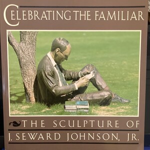 May include: A book cover with the title "Celebrating the Familiar: The Sculpture of J. Seward Johnson, Jr.". The cover features a bronze sculpture of a man sitting under a tree, reading a book.