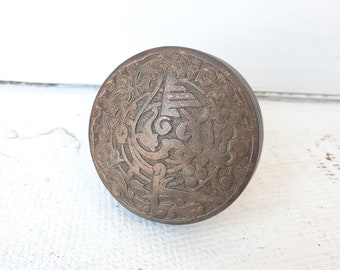 May include: A round, brass knob with an intricate, engraved floral design.