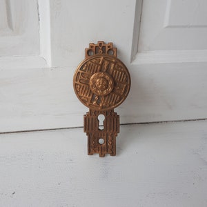 May include: A vintage brass door knob with an ornate design. The knob features a circular plate with intricate details and a keyhole.