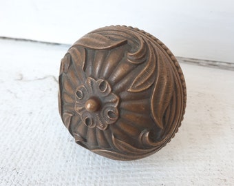 May include: A round, ornate, bronze door knob with a floral design.