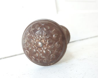 May include: A vintage, ornate, brown metal door knob with a floral design.