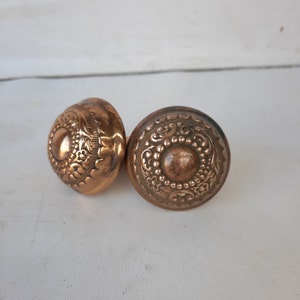 May include: Two antique copper door knobs with intricate floral designs.