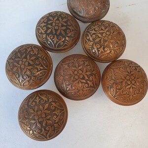 May include: Six antique door knobs with intricate floral designs. The knobs are made of a dark copper metal and have a worn, aged finish.