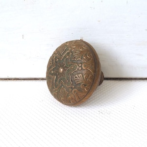 May include: A vintage brass door knob with an intricate floral design. The knob has a green patina and is in good condition.