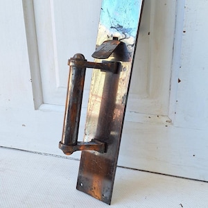 May include: An antique door handle and plate with a weathered, aged appearance. The handle is cylindrical, and the plate is rectangular with a keyhole. The metal has a dark, tarnished finish, suggesting age and use. A vintage hardware piece.