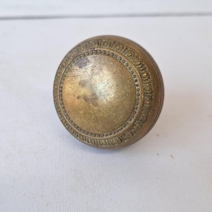 May include: A brass door knob with an ornate design around the edge.