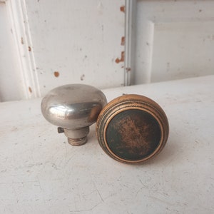 May include: Two antique door knobs, one silver and one brass with a green center.