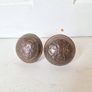 May include: Two antique brass door knobs with a decorative floral design.