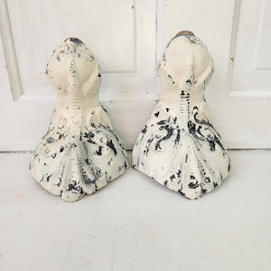 May include: Two white cast iron claw feet with black painted details. The feet are in a distressed style with chipped paint.