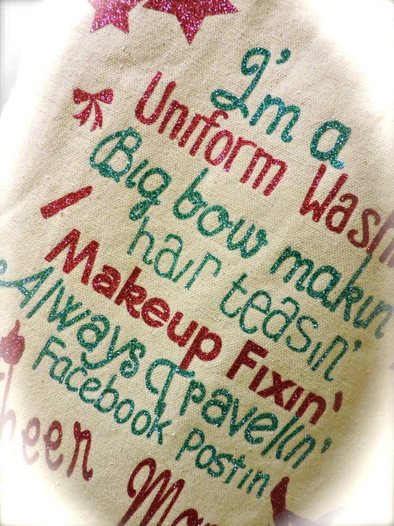 May include: A beige canvas tote bag with the text "I'm a Uniform Was Big bow makin hair teasin Fixin Makeup Always travelin' Facebook Postin'" in red and green glitter.