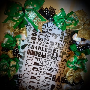 May include: A white background with black text that reads "Cheer" and other cheerleading terms. The background is surrounded by green, gold, and black cheer bows.