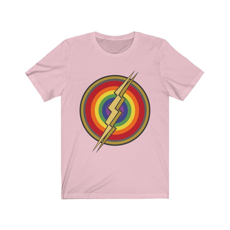 May include: Pink short-sleeved t-shirt with a rainbow and lightning bolt graphic. The graphic is in the center of the shirt and is a stylized version of the Flash logo.