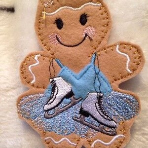 May include: A gingerbread person wearing a blue dress and ice skates. The gingerbread person has a smiling face with rosy cheeks and a gold crown.