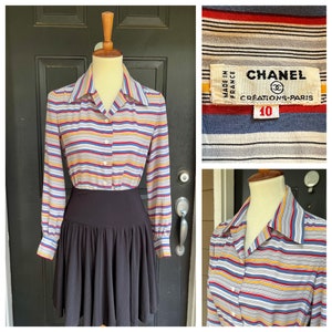 May include: A vintage button-down shirt with horizontal stripes in red, blue, yellow, and gray. The shirt is paired with a black skirt. The Chanel label is visible, indicating the brand and size 10.