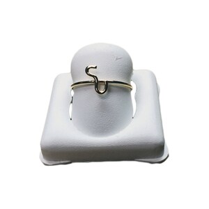 May include: A gold-colored ring with the letter "S" formed into the band.