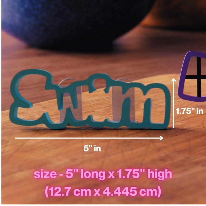 Op de afbeelding: Blauwe plastic koekjesvormer in de vorm van het woord "Swim" met een lengte van 12,7 cm en een hoogte van 4,45 cm.
