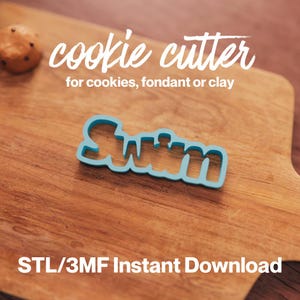 Puede incluir: Cortador de galletas de plástico azul en forma de la palabra "Swim" sobre una superficie de madera.  "cookie cutter for cookies, fondant or clay" y "STL/3MF Instant Download" están escritos en blanco sobre la superficie.