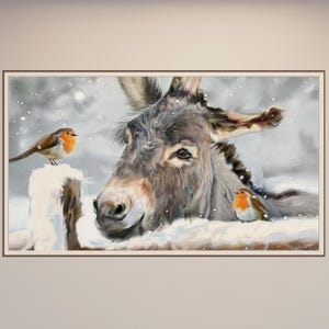 May include: A framed painting shows a donkey in a snowy scene, with two robins. The donkey has grey fur and is surrounded by snow. The robins have orange breasts and brown wings. The artwork is framed in a brown border.
