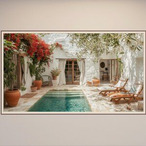 Può includere: Fotografia incorniciata di una scena all'aperto tranquilla. Una piccola piscina con acqua turchese è circondata da un patio in pietra. Le pareti in stucco bianco sono adornate da fiori rossi e verde. Sedie a sdraio in legno e vasi in terracotta contribuiscono all'atmosfera serena.