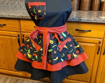 May include: A black apron with red and white polka dots and a red pocket. The apron has a tiered skirt with a chili pepper print.