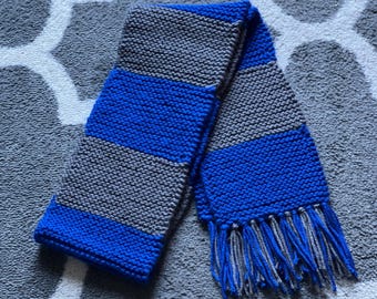 Könnte beinhalten: Ein gestrickter Schal in den Farben Blau und Grau mit Fransen an den Enden.