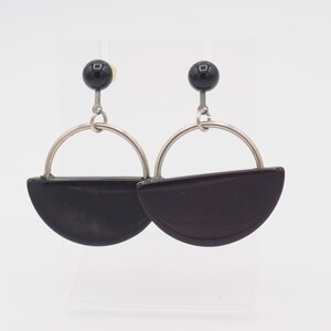 May include: A pair of black and silver earrings with a half-circle design. The earrings are made of metal and have a black bead at the top.