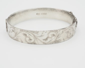 Könnte beinhalten: Ein silbernes Armreif-Armband mit einem gravierten Blumenmuster. Das Armband hat einen Scharnierverschluss und ist innen mit "925" gekennzeichnet.