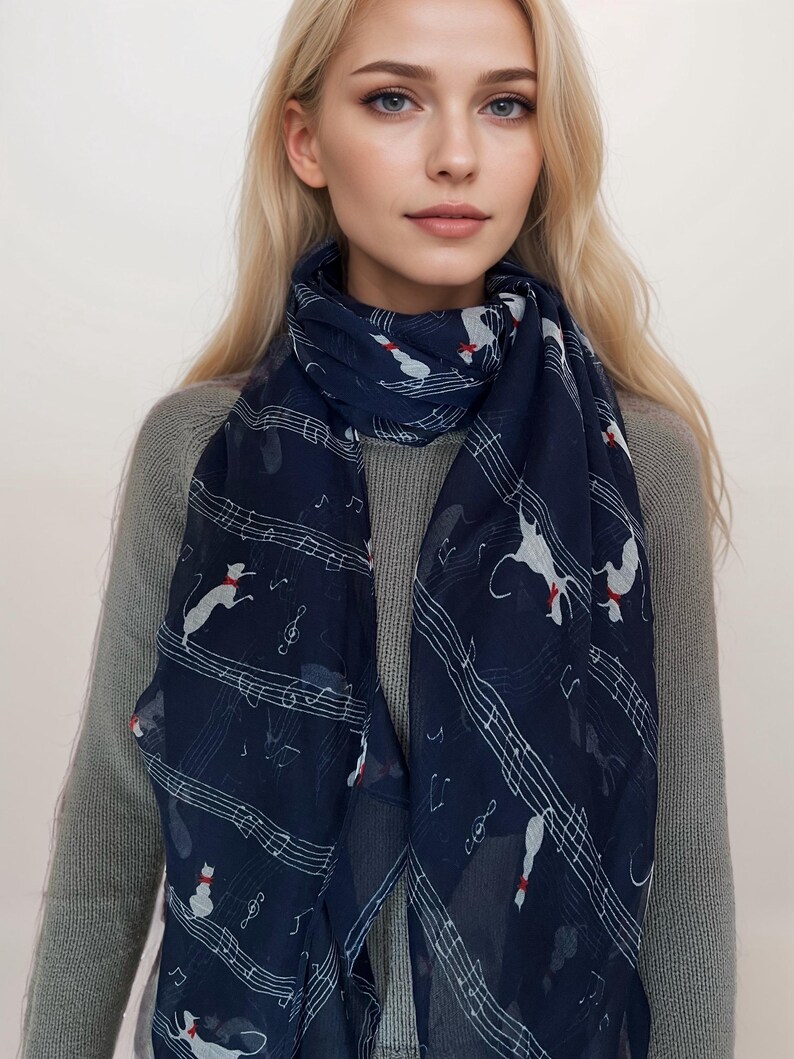 May include: A navy blue scarf with a white musical note and cat design. The scarf is made of a lightweight fabric and is perfect for adding a touch of style to any outfit.