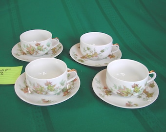 May include: Set of four white teacups and saucers with a green and brown maple leaf design. The cups and saucers have a gold trim.
