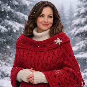 May include: A vibrant red crocheted poncho featuring an intricate cable knit pattern, a wide folded collar, and long fringe trim along the bottom edge. A silver-toned star-shaped brooch is pinned to the upper left side of the red garment.