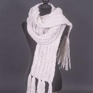 May include: A white crocheted scarf with long fringe tassels. The scarf is draped over a black mannequin.