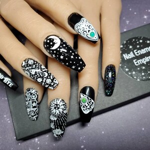 May include: Black and white nail art with a variety of designs, including a crescent moon, stars, a sun, a pentagram, and the words "Good Bye".