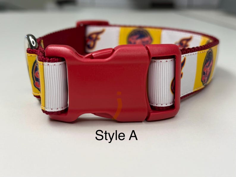 May include: Red dog collar with a red plastic buckle. The collar features a pattern of yellow, white, and maroon stripes with a logo. The text "Style A" is printed in black.
