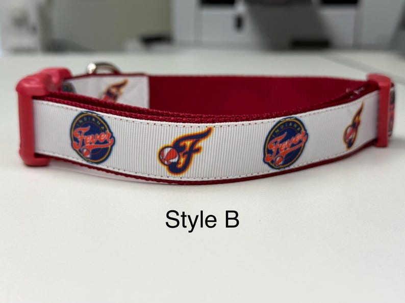 May include: A red and white dog collar with a team logo. The collar has a white ribbon with the team logo and the word "Fever" in a circular design. The inside of the collar is red, and the buckle is pink. The text "Style B" is at the bottom.