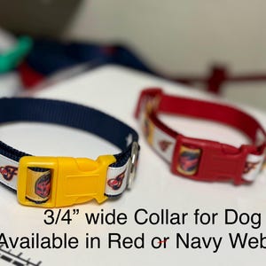 May include: Two dog collars, one navy blue and one red, each with a yellow buckle. The collars are 3/4 inch wide and feature a repeating pattern of a cartoon image on a white background. The navy collar has a yellow buckle, and the red collar has a red buckle.