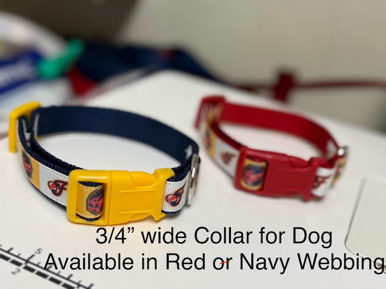 May include: Two dog collars, one navy blue and one red, each with a yellow buckle. The collars are 3/4 inch wide and feature a repeating pattern of a cartoon image on a white background. The navy collar has a yellow buckle, and the red collar has a red buckle.